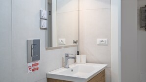 Ein modernes Badezimmer mit Waschbecken, Spiegel und Spender für Handtücher.