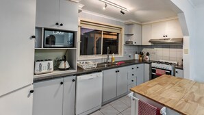 Een moderne keuken met witte kasten, een inbouwoven, een spoelbak en een raam met uitzicht.