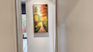 Een gang met een schilderij van een pad omzoomd door bomen.