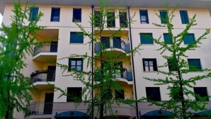 A multi-story building with balconies, a parking sign, and trees in front. - Residence of the TOLOMEI - SACILE (Sacile)