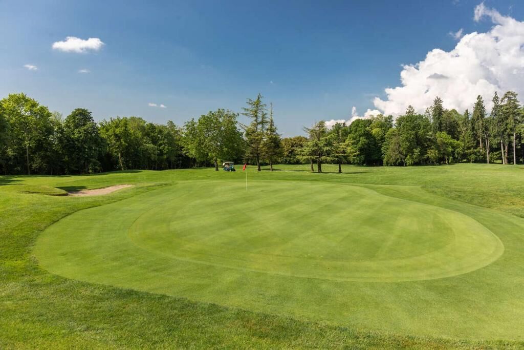 A golf course with a well-maintained green, sand bunkers, and a flagstick.