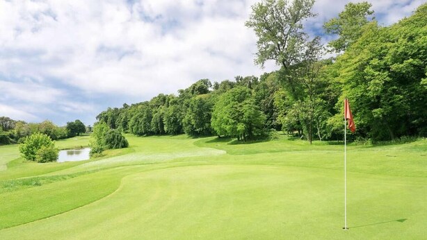 A golf course with a flagstick, trees, and a pond. - Residence of the TOLOMEI - SACILE (Sacile)
