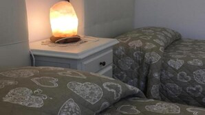 A bedroom with a nightstand, a bed with heart-patterned bedding, and a lit salt lamp. - Residence of the TOLOMEI - SACILE (Sacile)