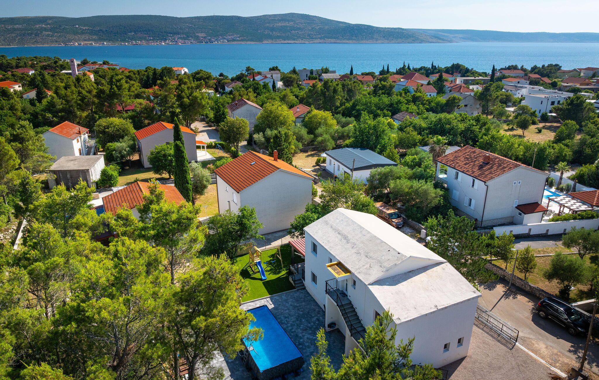 A coastal residential area with houses, a swimming pool, and a view of the sea.