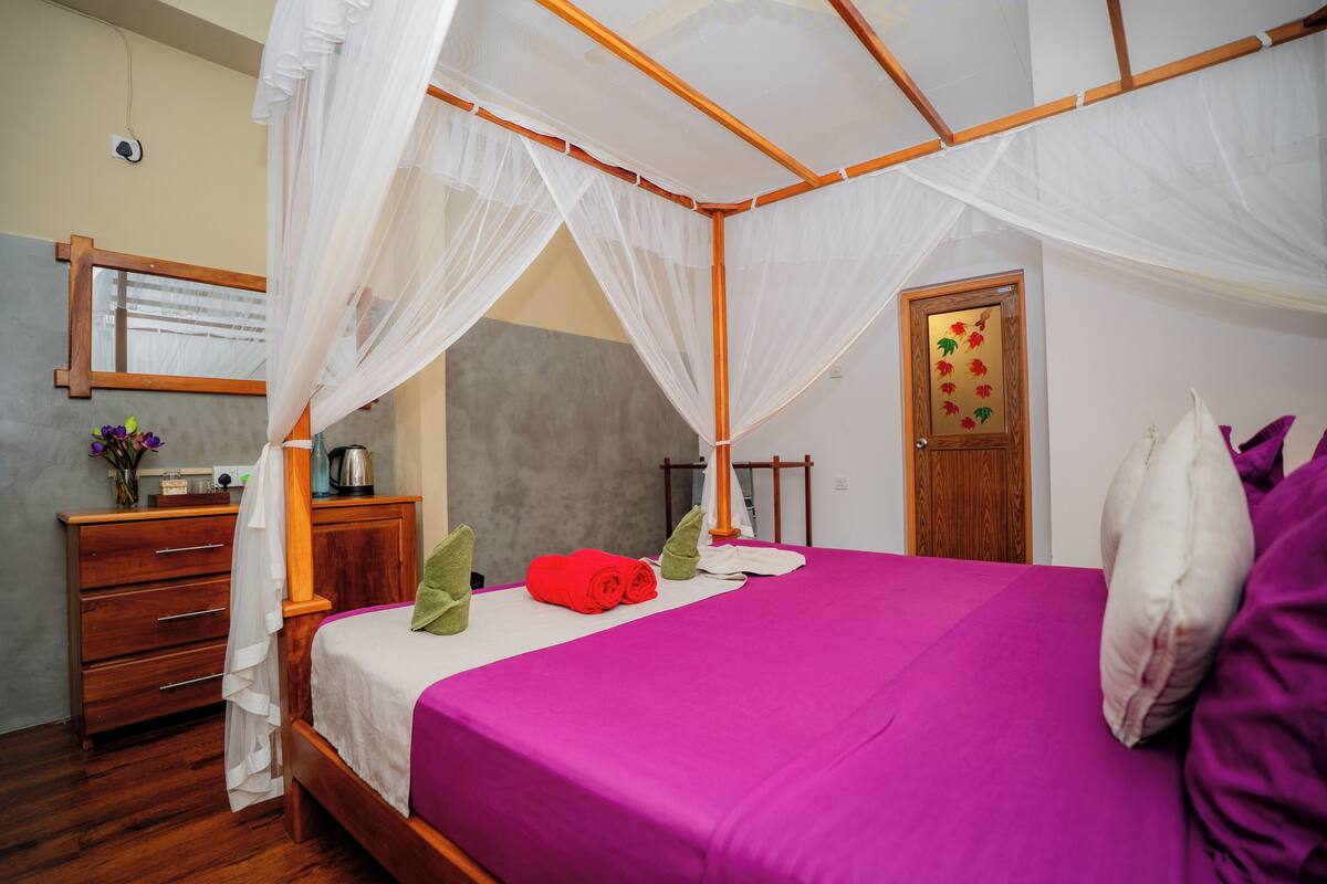 A room with a bed, a wooden dresser, a mirror, and a door with a floral design.