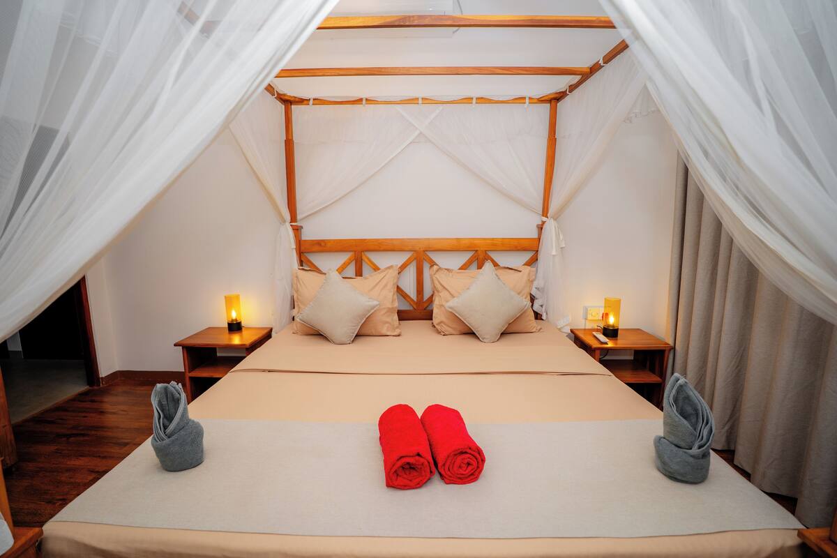 A bed with a canopy, two bedside tables with lamps, and towels on the bed.