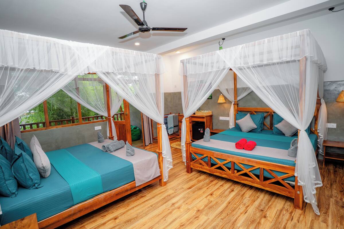 A room with two wooden beds, each with a canopy, and a ceiling fan.