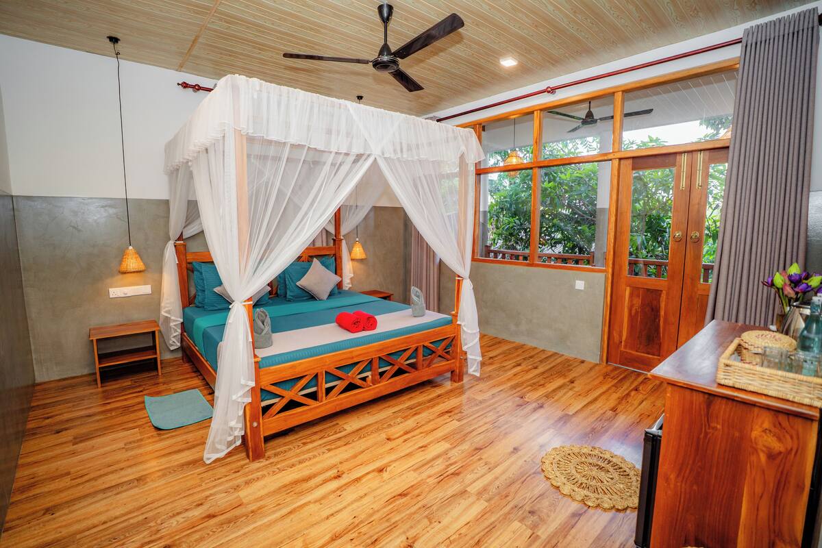 A room with a wooden bed, a ceiling fan, and a large window with curtains.