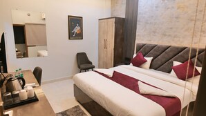 Quarto de hotel com uma cama grande, uma mesa com cadeira, um guarda-roupa e um espelho.