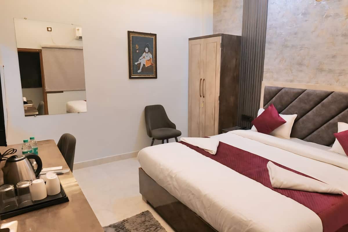 Hotellihuone, jossa on suuri sänky, työpöytä tuolilla, vaatekaappi ja peili.