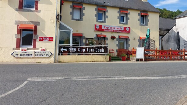 Un bâtiment avec une enseigne indiquant « Captain Cook », ce qui signifie qu’il s’agit d’un pub et d’un restaurant. Des panneaux de signalisation indiquent l’emplacement du parking et des lieux à proximité.