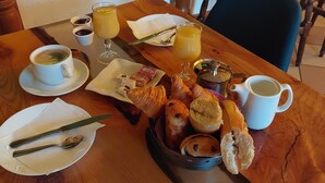 Une table de petit-déjeuner avec des croissants, des viennoiseries, une tasse de café et des verres de jus de fruits.