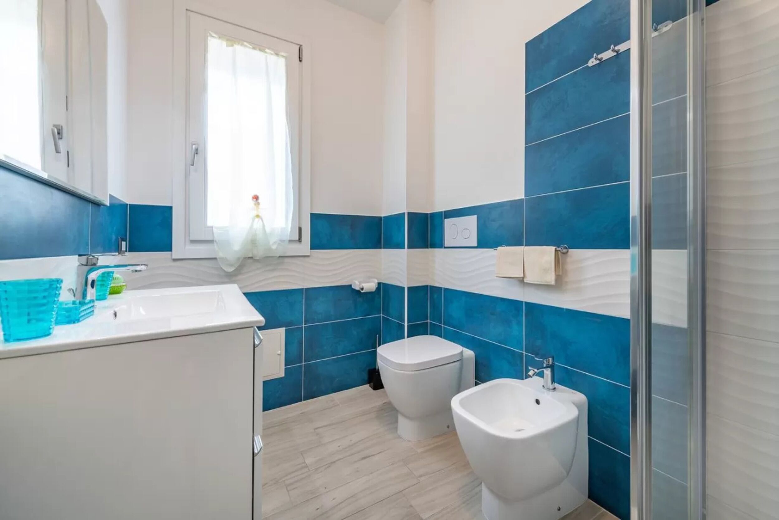 Un baño con lavamanos blanco, un bidé y zona de ducha.