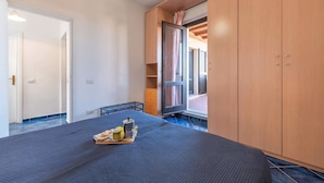 Een slaapkamer met een bed, een houten garderobe en een klein tafeltje met ontbijtartikelen.