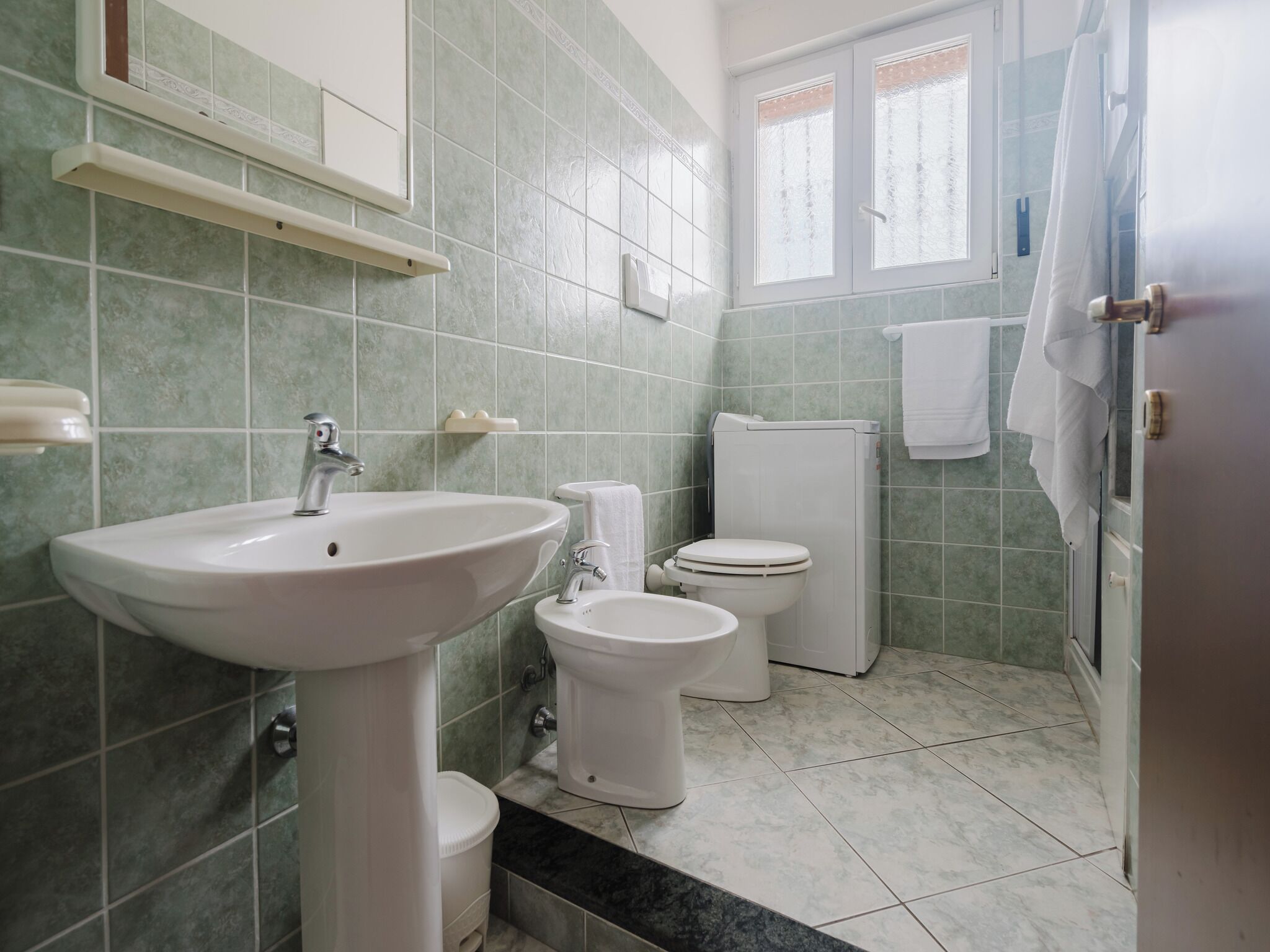 A bathroom with a sink, toilet, bidet, and a shower area.
