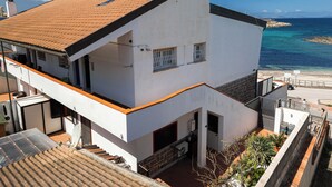 A modern two-story building with a flat roof, satellite dishes, and a view of the sea.