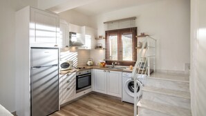 Eine kompakte Küche mit Einbauofen, Waschmaschine und Edelstahl-Kühlschrank.