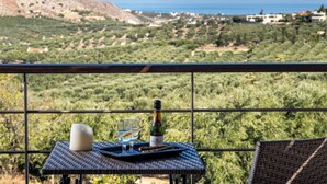 Ein Tisch mit Champagnerflasche, Gläsern und Kerze auf einem Balkon mit Blick auf eine gebirgige Landschaft.