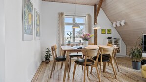 A dining area with a wooden table and chairs, a window with curtains, and a ceiling with exposed beams. - Cozy apartment in Nordborg (Nordborg)