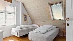 A room with two single beds, a wooden ceiling, a window with blinds, a poster on the wall, and a chair. - Cozy apartment in Nordborg (Nordborg)