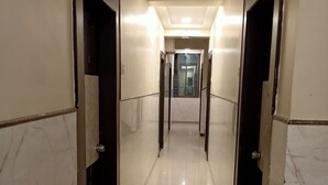 A corridor with marble walls and doors, leading to a staircase. - Hotel Palkhi (Rahata)