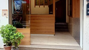 The entrance to a hotel with a reception desk, a staircase leading inside, and a potted plant outside. - Hotel Palkhi (Rahata)
