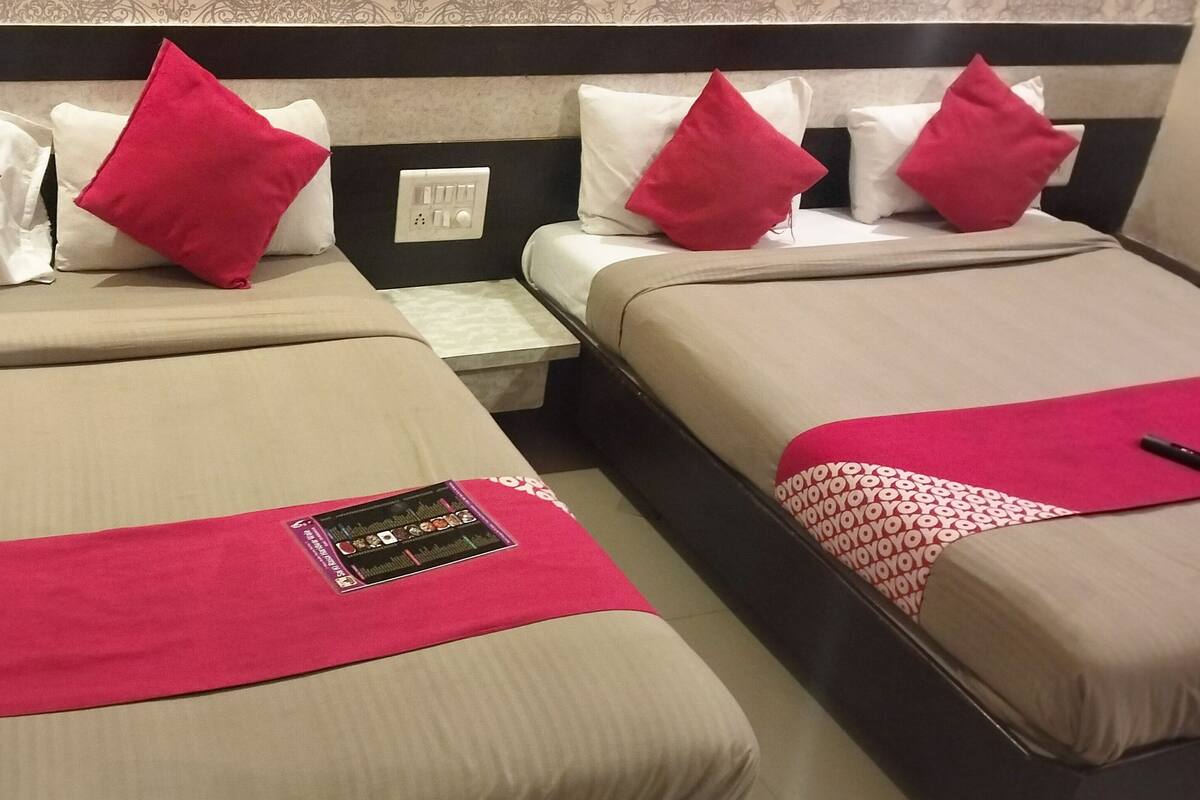 Dos camas con almohadas rojas y blancas, una mesita de noche y un enchufe.