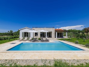 A modern house with a swimming pool, outdoor seating, and a garden.
