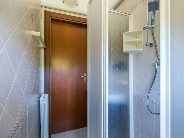A bathroom with a shower, a door, and tiled walls.