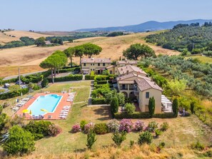 A villa with a swimming pool, surrounded by lush greenery and olive groves.