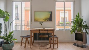 A room with a wooden desk, two chairs, a large window, and a potted plant. - Urban Spring (Madrid)