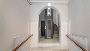 A marble staircase with a wooden handrail leading to a door at the top. - Urban Spring (Madrid)