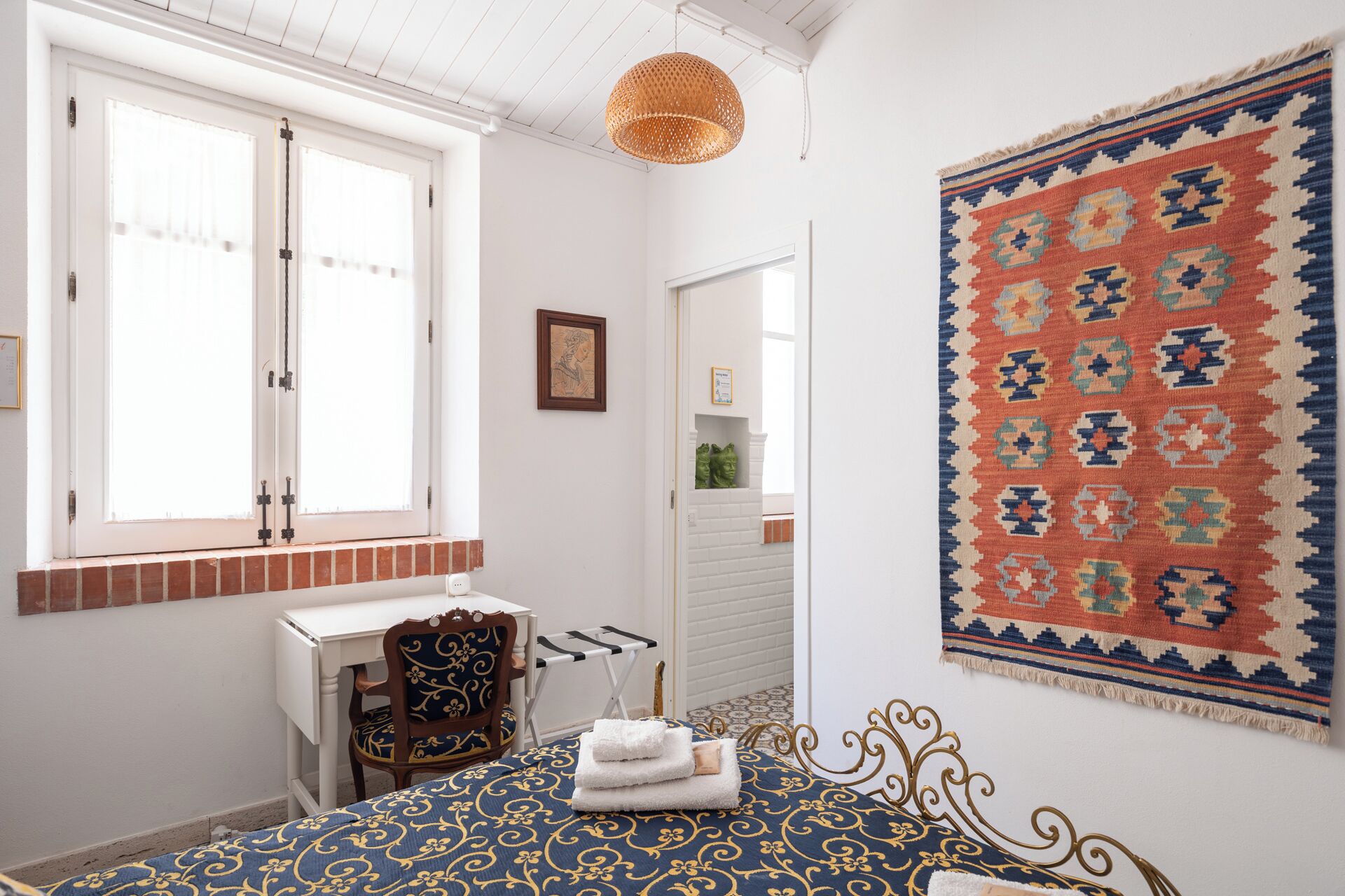 A room with a bed, a desk, and a large rug.