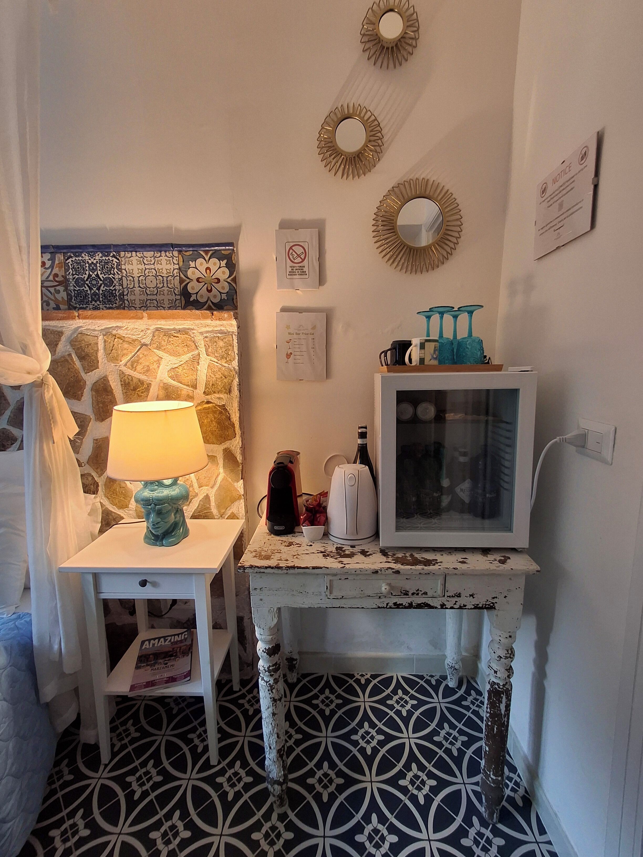 A cozy room with a stone wall, a small table with a lamp, a television, and a decorative mirror.
