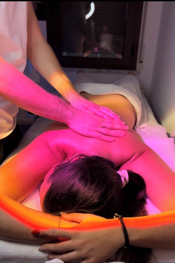 A person lying on a massage table receiving a back massage.