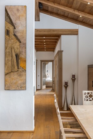 Ein Flur mit Holzboden, ein Essbereich mit Tisch und ein Gemälde an der Wand.