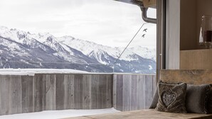Un banco de madera con vista a montañas nevadas a través de una ventana.