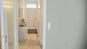 A narrow hallway with a wooden floor, a small sink with a potted plant, and a door on the left. - Relaxing vacation in the Panorama Whg. 8 - near the beach and the sea! (Grömitz)