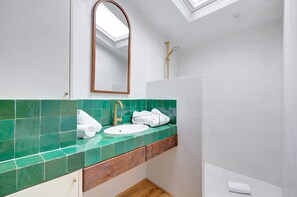 Un baño con tragaluz, un lavabo y una ducha.