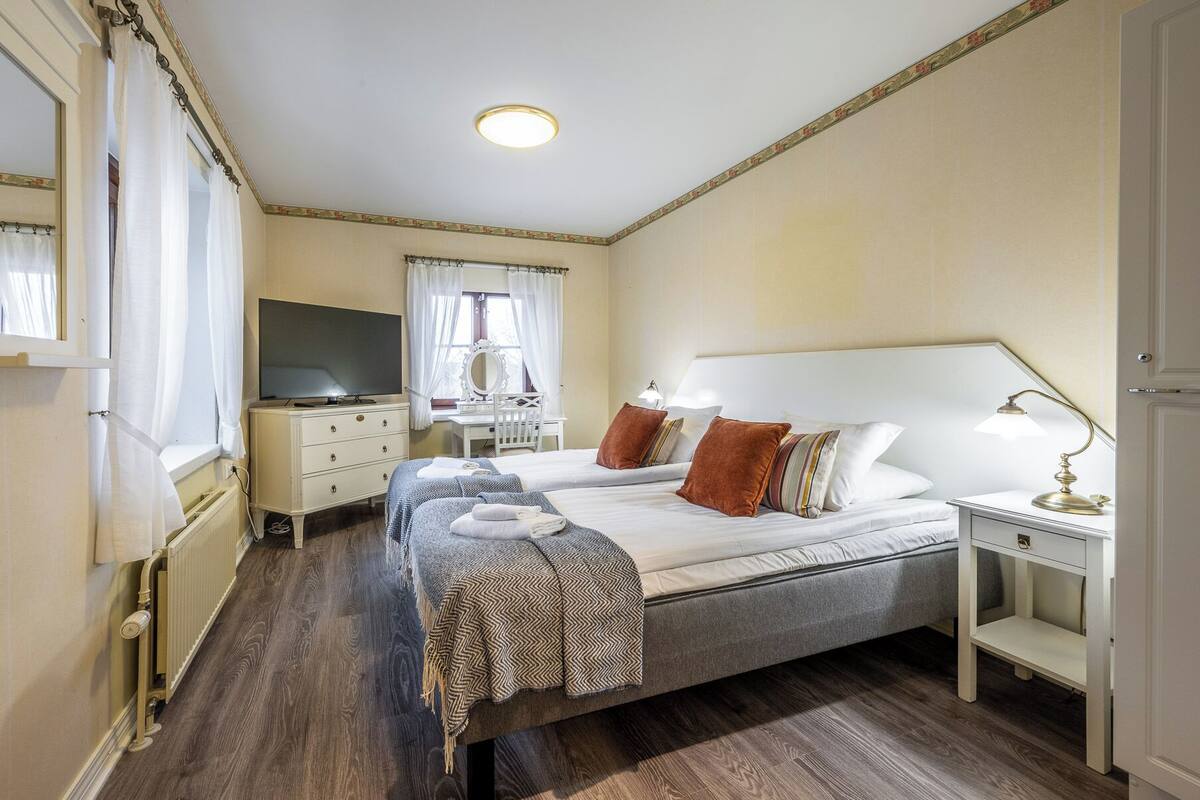 Une chambre d’hôtel comprenant un lit, des tables de chevet, une télévision, un bureau et un miroir.