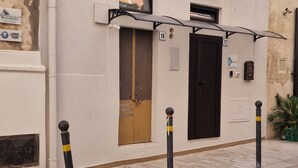 A building with a white facade, numbered doors, and a small window with a shutter. - CAMPANILE17 BED AND BREAKFAST 2 BEDS DOUBLE ROOM , 20MT SEA (Manfredonia)