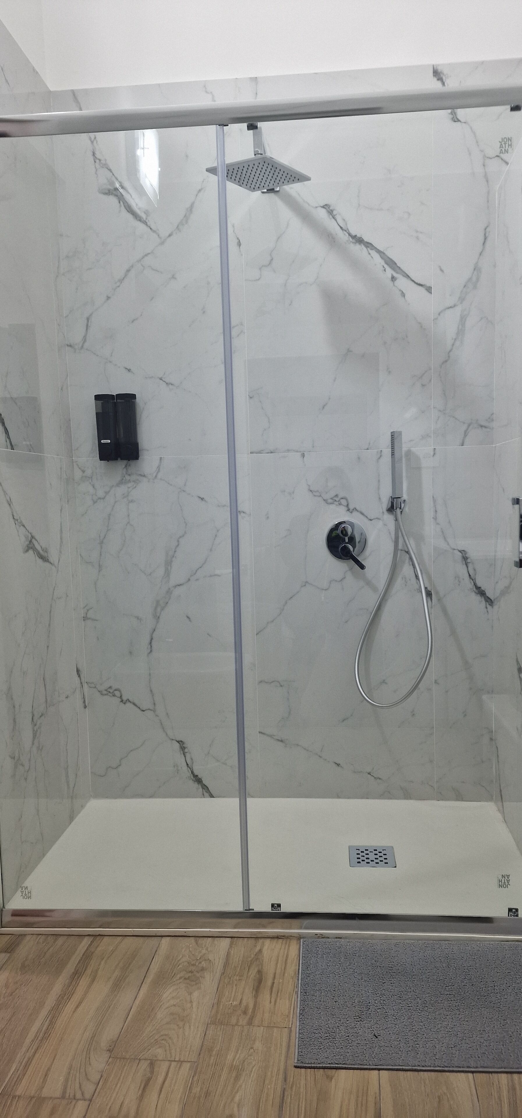 Eine moderne Duschkabine mit Glastür, Handbrause und Bedienfeld.