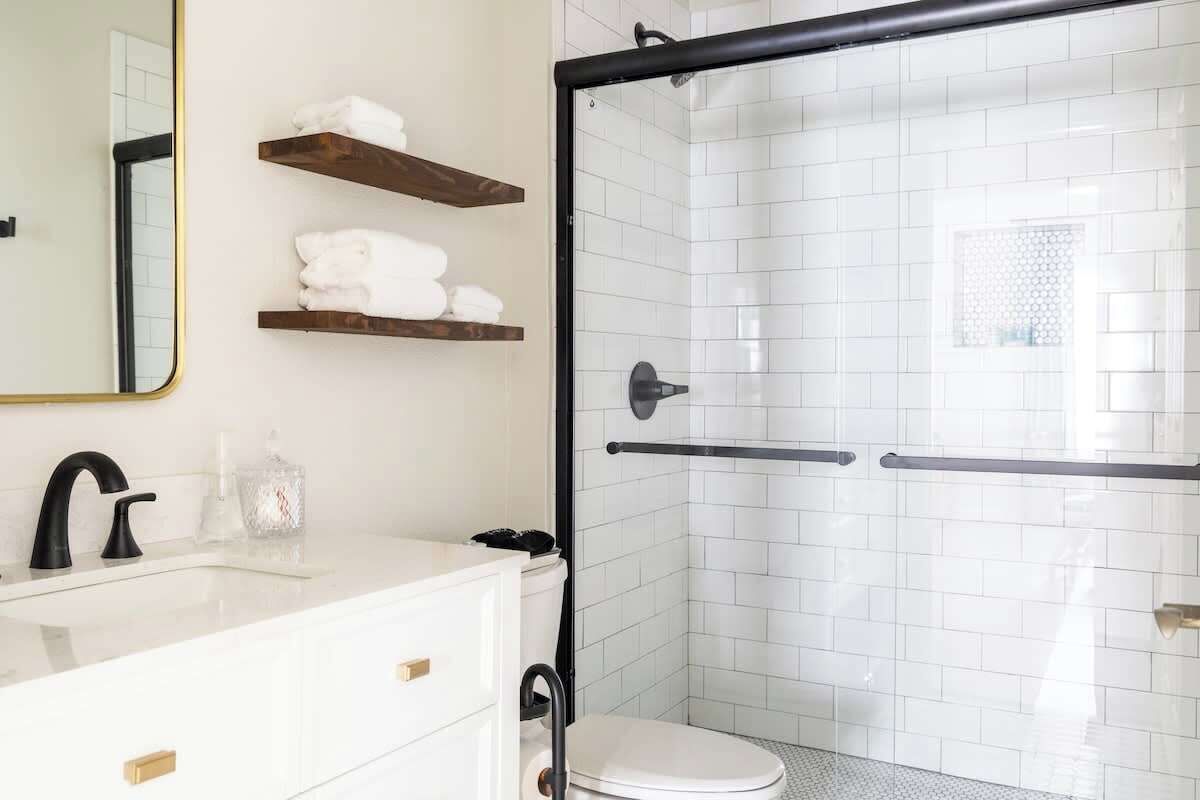 A modern bathroom with a white sink, black faucet, and a glass shower enclosure.