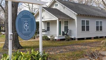 A white house with a porch, a sign for The Grace Inn, and a tree in the foreground.