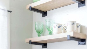 Een keuken met houten planken waarop drinkglazen en een koffiezetapparaat staan.