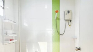 A small, clean bathroom with a toilet, a shower, and a shelf with toiletries.