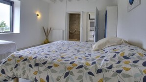 Ein Schlafzimmer mit einem Bett, einem Fenster, einer Tür zu einem Badezimmer und einer Wandleuchte.