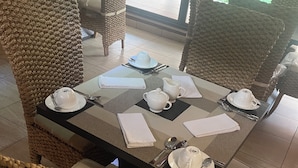 A dining area with wicker chairs and a table set for four. - Trois Ore Residences  (Ibadan)