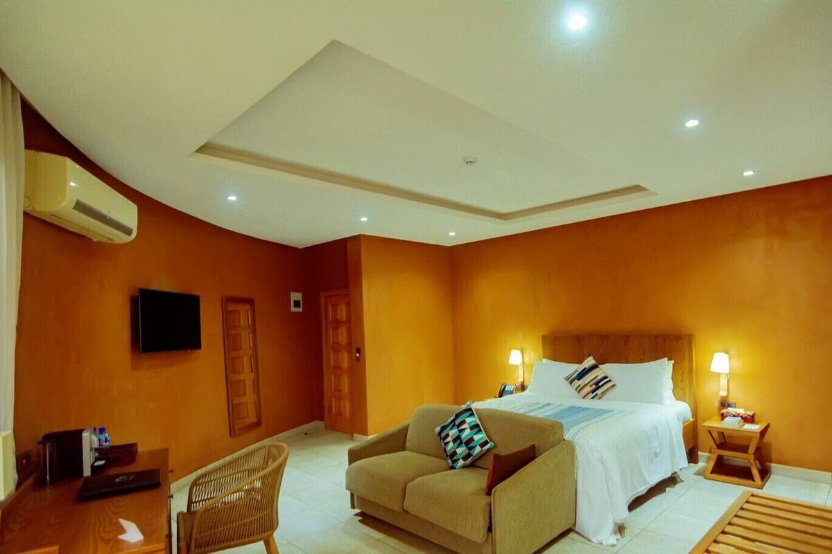 A hotel room with a bed, a sofa, a TV, and a desk with a chair.
