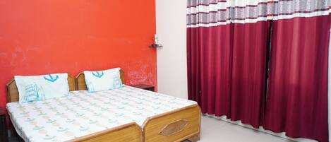 Una habitación con una cama, una pared roja y una ventana con cortinas rojas.